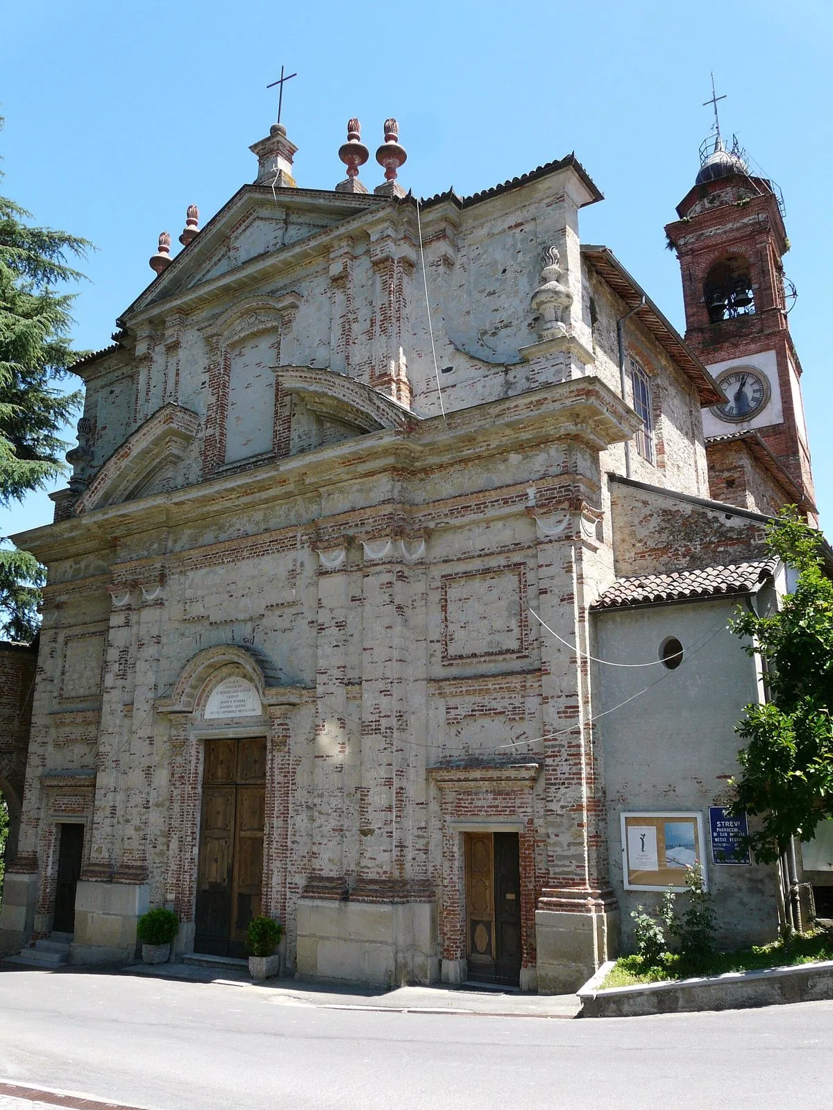 Facciata in mattoni della chiesa parrocchiale di San Michele Arcangelo a Strevi con il campanile e l'orologio