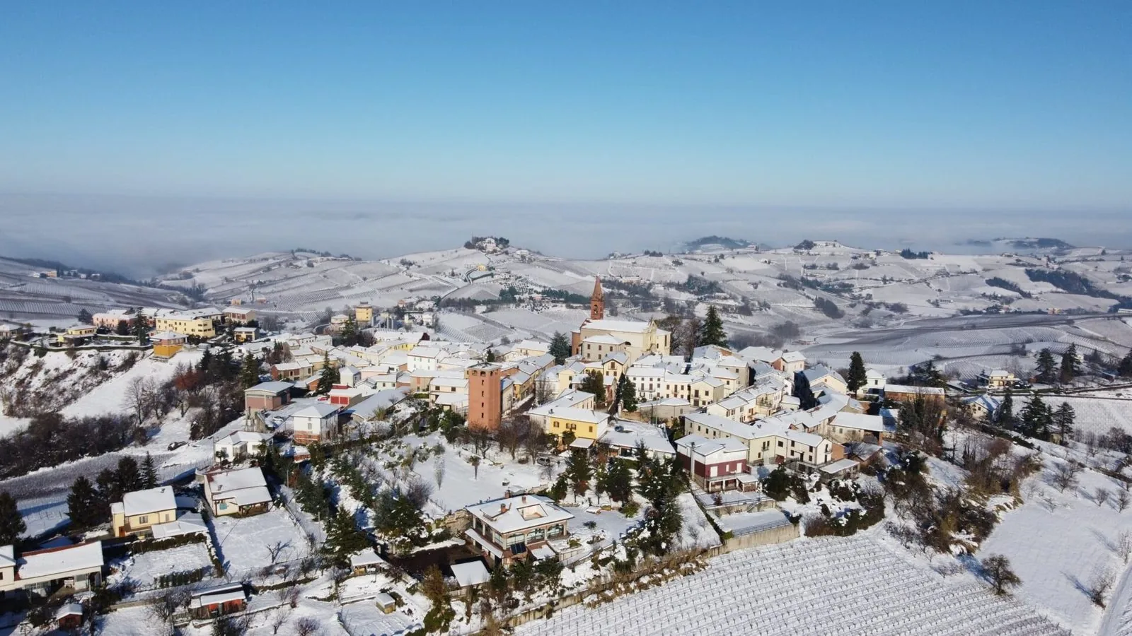 Il paese di Castel Rocchero e le colline vitate coperte di neve, con la nebbia nelle valli sullo sfondo
